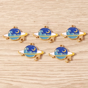 Five blue enamel Saturn planet pendants with moon and star details on wood background
