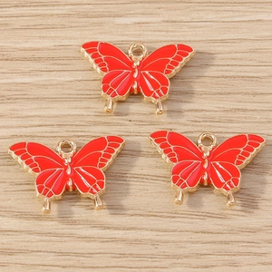 Détails de trois breloques papillon en émail rouge avec bordure métallique dorée