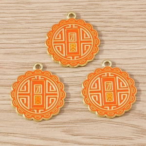 Detailed close-up of three orange enamel mooncake charms with Reunion gold lettering