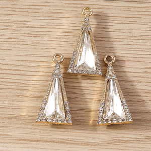 Detailed view of three gold geometric triangle crystal pendants on a light wood surface