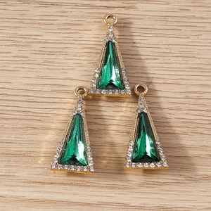 Macro detail of three golden triangle crystal pendants with emerald green center and rhinestones