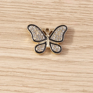 Détail macro du pendentif papillon avec émail noir et cristaux clairs sur métal doré