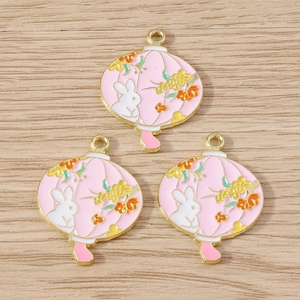 Detail of three pink enamel Chinese lantern charms with white rabbit and floral motifs