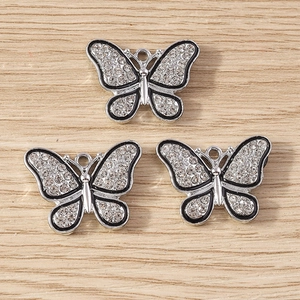 Trois pendentifs papillon élégants sertis de strass brillants sur un fond de bois
