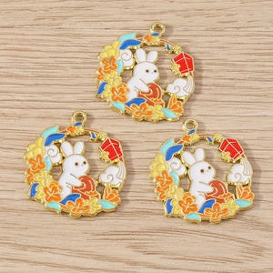 Detail of Chinese rabbit mooncake alloy charms with colorful enamel on wood background