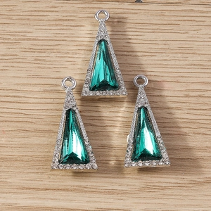 Macro shot of green triangle crystal charms with white rhinestones and silver base