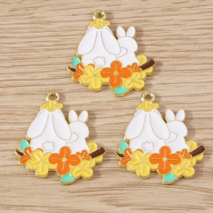 Three enamel rabbit flower charms for DIY jewelry making on a light wood background