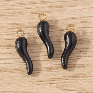 Close-up of black cornicello charms with gold rings on a natural wood surface
