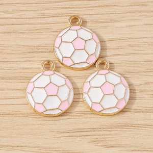 Close-up of pink and white soccer ball pendants with gold metal frames for DIY crafts