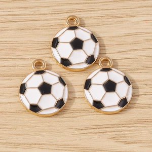 Three gold-plated football charms with black and white enamel on a light wood background