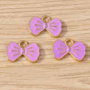 Detailansicht von drei lila Emaille-Schleifenanhängern mit Goldrand für DIY-Schmuck