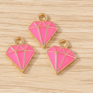 Roze ruitvormige hangers met goudkleurige rand op hout voor het zelf maken van sieraden