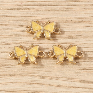 Detailed view of three yellow butterfly enamel connectors for DIY jewelry making