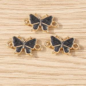 Detail of three black enamel butterfly charms with gold metal loops for DIY jewelry making
