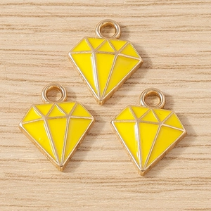Macro-opname van drie gele emaille diamantvormige hangers op houten ondergrond