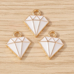 Drie vergulde diamantvormige hangers met wit email op een lichte houten achtergrond