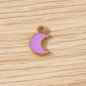 Detailed macro view of a gold alloy crescent moon charm with light purple enamel inlay