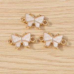 Close-up of three pink enamel butterfly connectors for DIY jewelry making on wood
