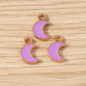 Detailed macro shot of purple enamel moon charms with gold metal edges for DIY jewelry making