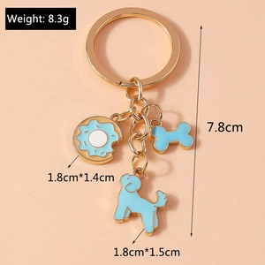 Golden keychain with light blue enamel cartoon bone and poodle charms on peach background