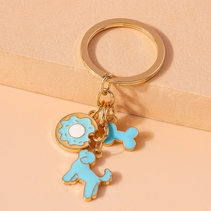 Detailed close-up of blue cartoon dog, donut, and bone pendants on a gold keychain