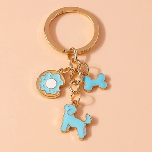 Detail of gold metal keychain with blue enamel donut, bone and poodle dog charms