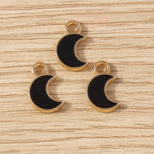 Detail of three black enamel moon pendants with gold metal edges and top loops