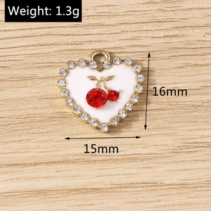 Détail d'un pendentif cœur avec cerises en strass rouges et bordure dorée, 15x16mm pour bijoux
