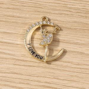 Détail d'un pendentif demi-lune doré avec strass et gravure I Love You pour la bijouterie