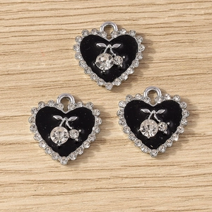 Détail de breloques cerises en forme de cœur avec émail noir et bordure en strass argenté