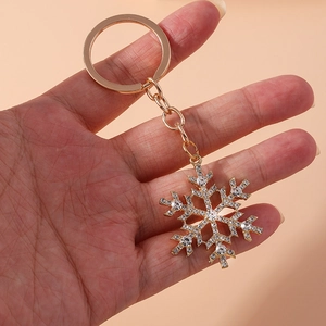 Golden snowflake keychain with sparkling rhinestones on a warm pink background