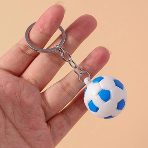 Close-up of a blue and white football keychain held in hand for size comparison