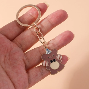 Detail view of cartoon birthday bear keychain with party hat held in hand