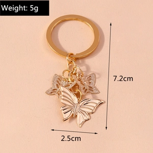 Golden butterfly keychain accessory with white enamel pendant and circular ring