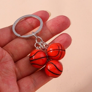 Close-up of three orange basketball pendants with silver metallic keyring in hand