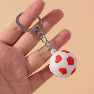 Handheld view of a red and white mini soccer keychain with realistic textured details