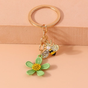 Close-up of golden bee pendant with pearls and green flower charm for keychain
