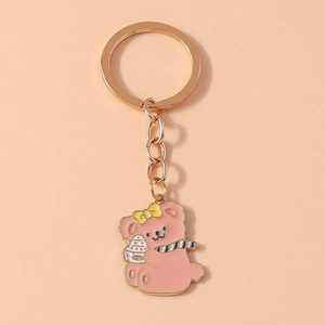 Close-up of pink enamel cartoon bear keychain with golden ring and blue striped scarf
