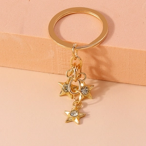 Close-up of golden star keychain with rhinestones on a pink geometric stand