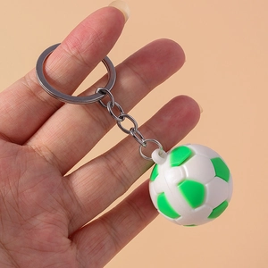 Detail showing hand holding a white and green football keychain with silver metal ring