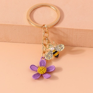 Detail of a gold bee keychain with sparkling rhinestones and a purple flower charm