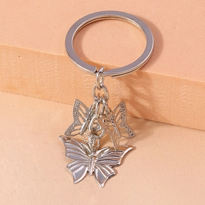 Detail view of silver alloy butterfly keychain with solid and hollow pendants on a ring