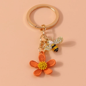 Macro shot of gold-tone bee charm with pearls and red floral keychain accessory