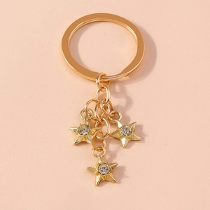 Detailed close-up of golden metal star keychain with three sparkling crystal pendants