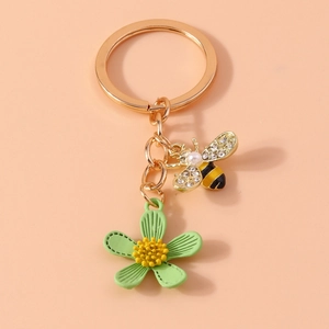 Detail of bee keychain with pearls and crystals on a polished golden metal ring