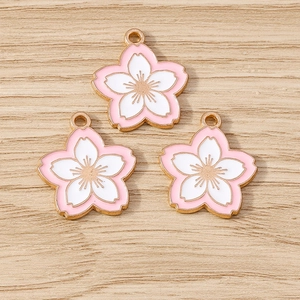 Close-up of three pink and white enamel cherry blossom charms with gold metal edges