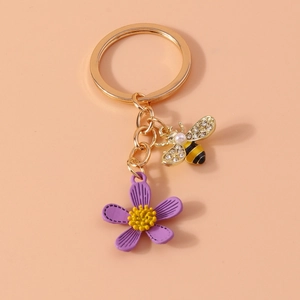 Close-up of golden bee keychain with purple flower charm and sparkling rhinestones
