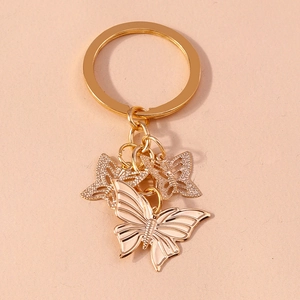 Detail of golden butterfly keychain featuring solid textured and hollow wing pendants