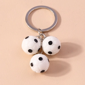 Detail view of silver keyring with three mini 3D football pendants on a matte surface