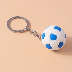 Close-up of a blue and white football keychain with silver metal ring on peach background